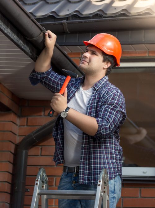 a person in a hard hat holding a hammer and a pipe
